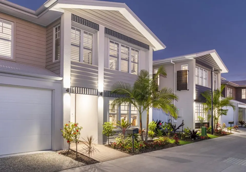 Two-storey townhouses at dusk, with the lights on and a landscaped path.
