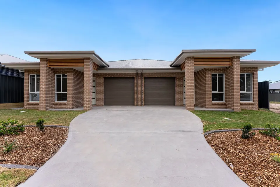 Two brick homes side by side, each with its own garage and front door.